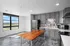 Modern kitchen with sleek gray cabinetry, stainless steel appliances, and a large wooden island, featuring a bright window with scenic views.