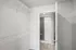 Spacious walk-in closet with wire shelving, connected to a modern bathroom featuring a sleek shower design.