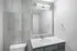Modern bathroom featuring elegant gray tile, a sleek white countertop, and contemporary lighting.