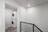 Modern hallway with a sleek railing leading to a bright laundry area featuring a stacked washer and dryer.