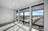 Bright and airy apartment room with large windows offering a stunning cityscape view, featuring modern tile flooring and abundant natural light.