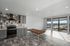 Modern open kitchen and living area with sleek gray cabinetry, tiled backsplash, and large sunny windows offering stunning views.