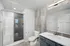 Modern bathroom featuring a spacious walk-in shower, elegant vanity, and a large mirror with contemporary lighting.