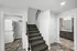 Modern apartment entryway featuring a carpeted staircase, in-unit laundry area, and a sleek bathroom with contemporary fixtures.