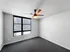 Bright and airy apartment bedroom featuring modern ceiling fan, plush carpeting, and large window for natural light.