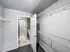 Spacious walk-in closet with ample shelving space, complemented by an en-suite bathroom featuring a modern shower.