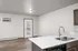 Bright and modern kitchen area with sleek countertops, stainless steel sink, and access to a balcony through glass doors.