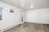Bright and spacious room with modern flooring, wall air conditioning unit, and large window for natural light.