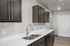 Modern kitchen with sleek dark cabinets, stainless steel sink, and elegant fixtures against a neutral backdrop.