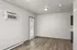 Bright and modern living space with sleek wood flooring and natural light, featuring an air conditioner and patio access.