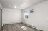 Bright, well-lit room with modern flooring and a window view, featuring a sleek wall-mounted air conditioner.