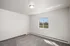 Bright and airy empty room with plush carpeting, neutral walls, and a large window overlooking scenic greenery.