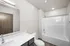 Sleek and modern bathroom featuring a pristine white bathtub, contemporary sink with a wide mirror, and elegant wood accents.