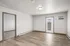 Bright and spacious living room with sleek wooden flooring and a modern glass door, offering ample natural light and a contemporary feel.