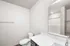 Bright and modern bathroom featuring sleek white countertops, a spacious mirror, and elegant fixtures.