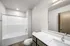 Modern bathroom with sleek fixtures, a large mirror, and a spacious bathtub, offering a bright and inviting atmosphere.