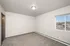 Bright and modern bedroom with plush carpeting, a large window with scenic views, and sleek ceiling light.