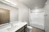 Modern bathroom with elegant white fixtures, spacious vanity, and a sleek bathtub, ideal for relaxation.