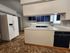 Modern kitchen with sleek white countertops, navy blue cabinets, and a spacious layout featuring a large refrigerator and ample natural light.
