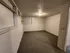 Cozy basement room with textured ceiling, soft carpeting, and built-in shelves, offering versatile space for various uses.