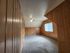 Cozy room with warm wooden paneling and soft carpet, enhanced by a ceiling fan and natural light from a large window.