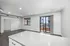 Modern open-concept living space with sleek finishes, large windows, and balcony access offering urban city views.