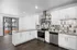 Modern kitchen with sleek white cabinetry, stainless steel appliances, and stylish tiled backsplash in a bright apartment space with large glass doors.