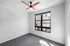 Bright and airy bedroom with large window and modern ceiling fan, offering a cozy and relaxing atmosphere.
