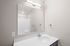 Chic modern bathroom with sleek countertop, large mirror, and bright lighting.