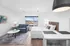 Modern studio apartment with stylish decor featuring a cozy bed, chic sofa, and contemporary artwork. Ample natural light floods the space, highlighting a sleek kitchenette and elegant furnishings.
