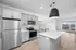 Contemporary kitchen featuring sleek gray cabinetry, stainless steel appliances, and a spacious island under modern lighting.
