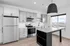 Modern kitchen with sleek stainless steel appliances, bright cabinetry, and a large island with built-in shelving, featuring abundant natural light from expansive windows.