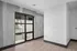 Modern industrial-style apartment with concrete walls, a large window, and sleek wooden flooring.