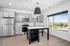 Modern kitchen with sleek gray cabinets, stainless steel appliances, and a spacious island, featuring large window with scenic views.