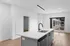 Modern apartment kitchen with sleek island, stylish faucet, bright wood floors, and large window offering ample natural light.