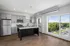 Modern kitchen with sleek appliances, ample cabinetry, and large windows offering a scenic view of lush greenery.