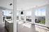 Bright, modern apartment with floor-to-ceiling windows, sleek kitchen island, and panoramic city views.