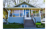 Charming blue house with welcoming front porch and lush garden, perfect for comfortable living.