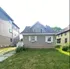 Charming two-story house with gray siding, featuring a green lawn and cozy front entrance.