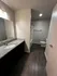 Modern apartment bathroom with sleek granite countertop, elegant sink, and warm wood-look flooring.