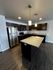 Modern kitchen with sleek dark cabinets, stainless steel appliances, and a spacious granite island, perfect for entertaining.