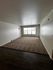 Bright and spacious living area with large window and cozy carpet, featuring mixed flooring for a stylish touch.