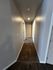 Inviting hallway with soft carpet flooring leading to multiple rooms, bathed in warm lighting.