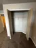 Contemporary apartment closet with open double doors, neutral tones, and plush carpet flooring.