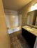 Modern bathroom with elegant granite countertop, sleek fixtures, and a spacious bathtub under warm lighting.