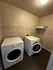 Modern laundry room with sleek white appliances and elegant wood flooring.
