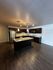 Modern kitchen featuring sleek dark wood cabinetry, granite countertops, stainless steel appliances, and elegant pendant lighting over a spacious island.