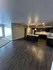 Spacious open-concept living area with modern dark flooring and elegant kitchen, perfect for entertaining.