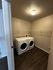 Modern laundry room with front-loading washer and dryer, enhanced by spacious shelving and sleek flooring.