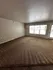 Bright living room with plush carpet, large window for natural light, and neutral walls, creating a cozy atmosphere.